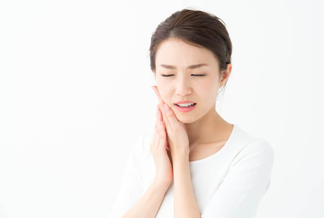 頬に手を当てて痛がっている女性
