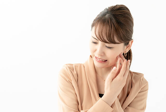 頬に手を当て痛がっている女性